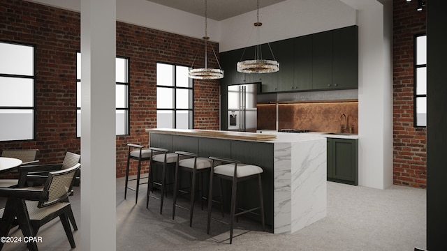 kitchen featuring backsplash, pendant lighting, brick wall, and stainless steel fridge