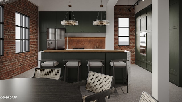 kitchen featuring brick wall, wall oven, stainless steel refrigerator with ice dispenser, rail lighting, and pendant lighting