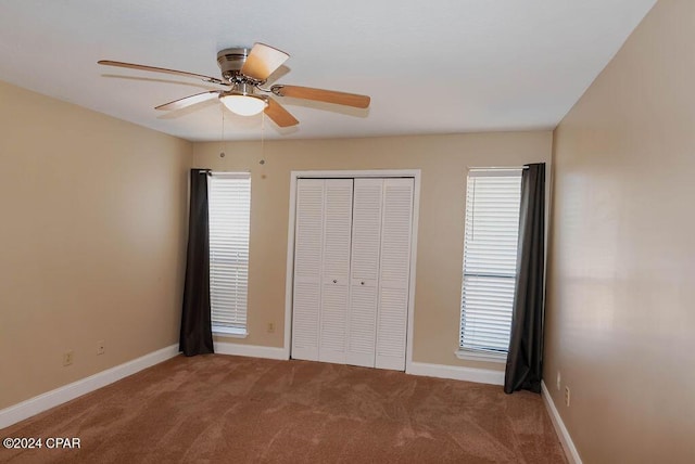 unfurnished bedroom featuring carpet floors, a closet, baseboards, and a ceiling fan