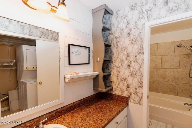 bathroom featuring stacked washing maching and dryer, shower / washtub combination, and vanity