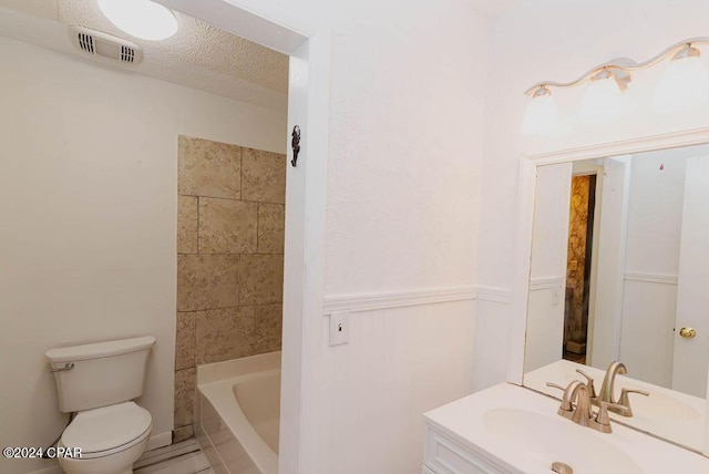 full bathroom with toilet, visible vents, a textured ceiling, and vanity