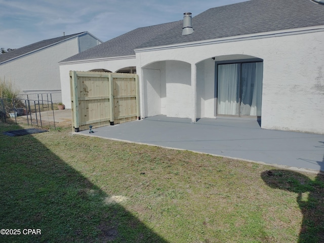 rear view of property with a lawn, a patio area, fence, and stucco siding