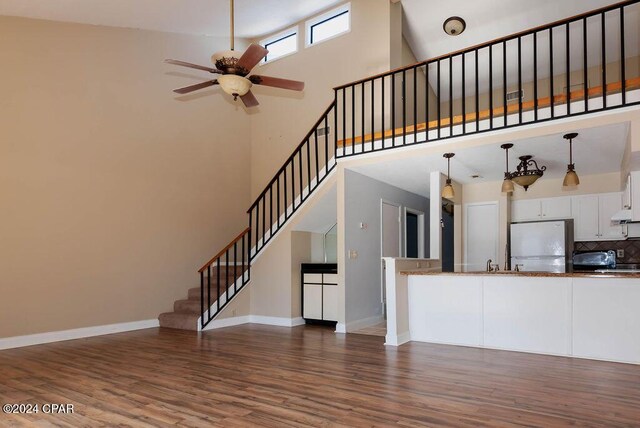 unfurnished living room featuring beamed ceiling, light wood-type flooring, high vaulted ceiling, and ceiling fan