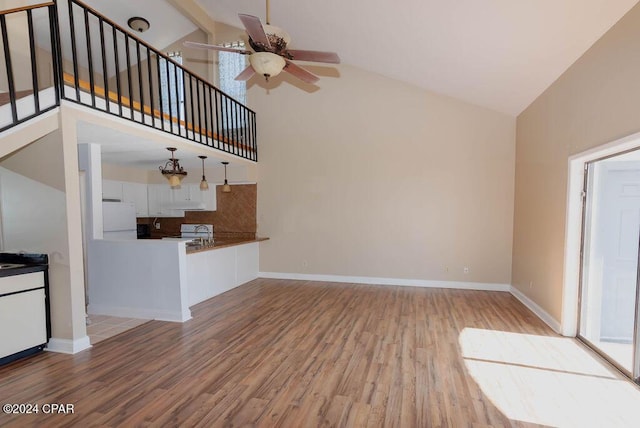 unfurnished living room featuring baseboards, high vaulted ceiling, ceiling fan, and wood finished floors