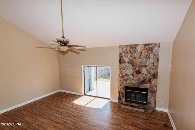 unfurnished living room with baseboards, lofted ceiling, ceiling fan, wood finished floors, and a stone fireplace