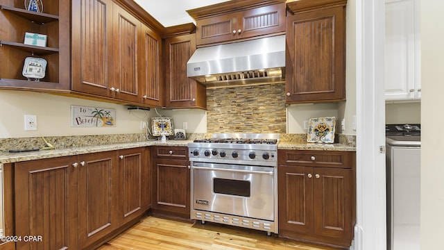 kitchen featuring washer / clothes dryer, light stone countertops, light hardwood / wood-style flooring, and luxury stove