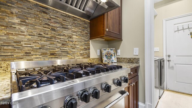 kitchen with custom exhaust hood, light stone counters, and stainless steel gas range