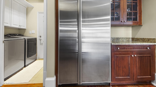 kitchen featuring light stone counters, independent washer and dryer, stainless steel fridge, hardwood / wood-style floors, and white cabinets