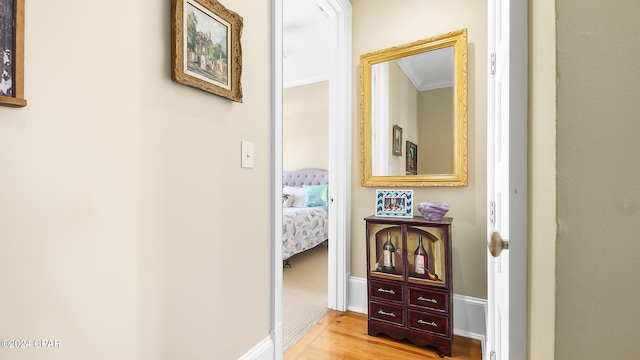 hall with light wood-type flooring and ornamental molding