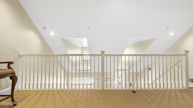 hallway with light colored carpet and lofted ceiling