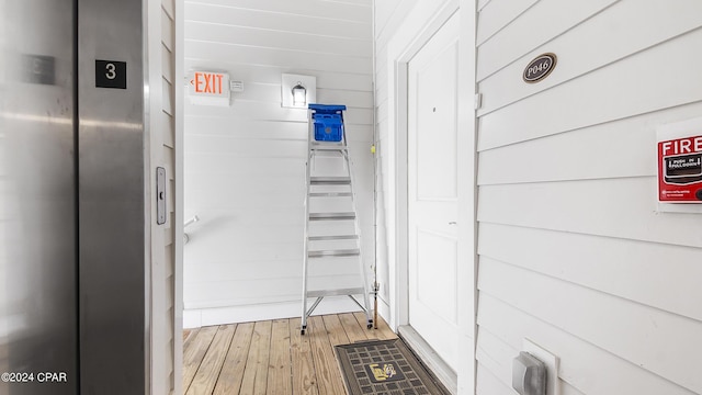 interior space featuring hardwood / wood-style floors, wood walls, and elevator