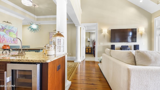 interior space with wet bar, dark hardwood / wood-style floors, ornamental molding, beverage cooler, and decorative columns