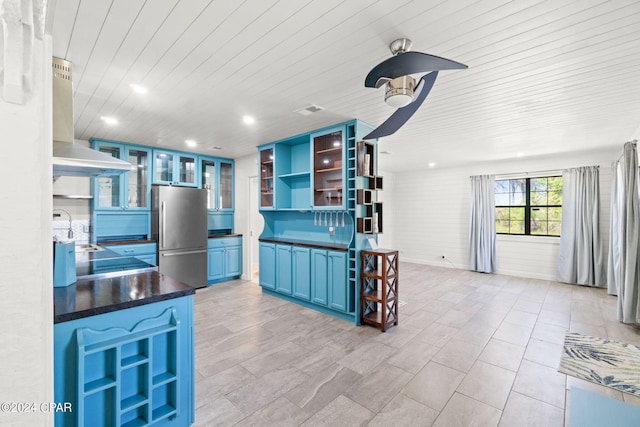 kitchen featuring stainless steel refrigerator, extractor fan, sink, blue cabinets, and light tile floors