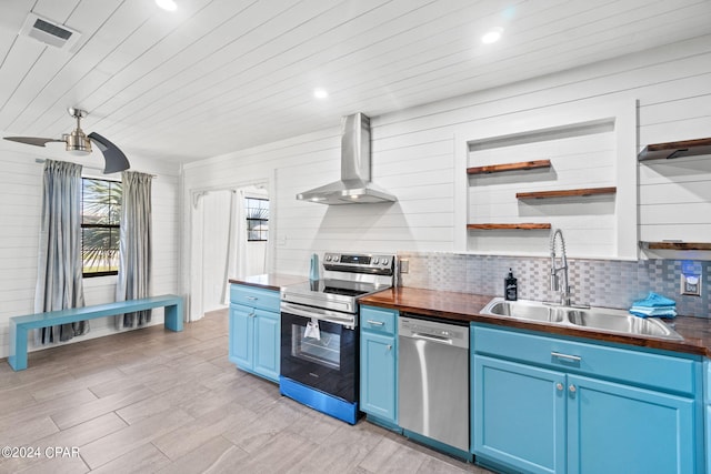 kitchen featuring electric range oven, wall chimney range hood, blue cabinetry, sink, and stainless steel dishwasher