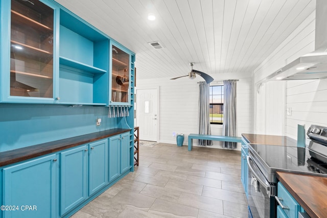 kitchen featuring wall chimney range hood, wood ceiling, stainless steel range with electric cooktop, butcher block counters, and blue cabinets