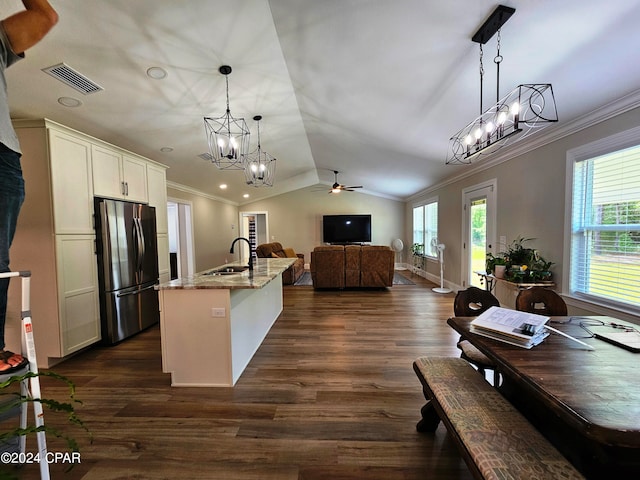 kitchen with dark hardwood / wood-style floors, pendant lighting, stainless steel refrigerator, light stone countertops, and ceiling fan with notable chandelier