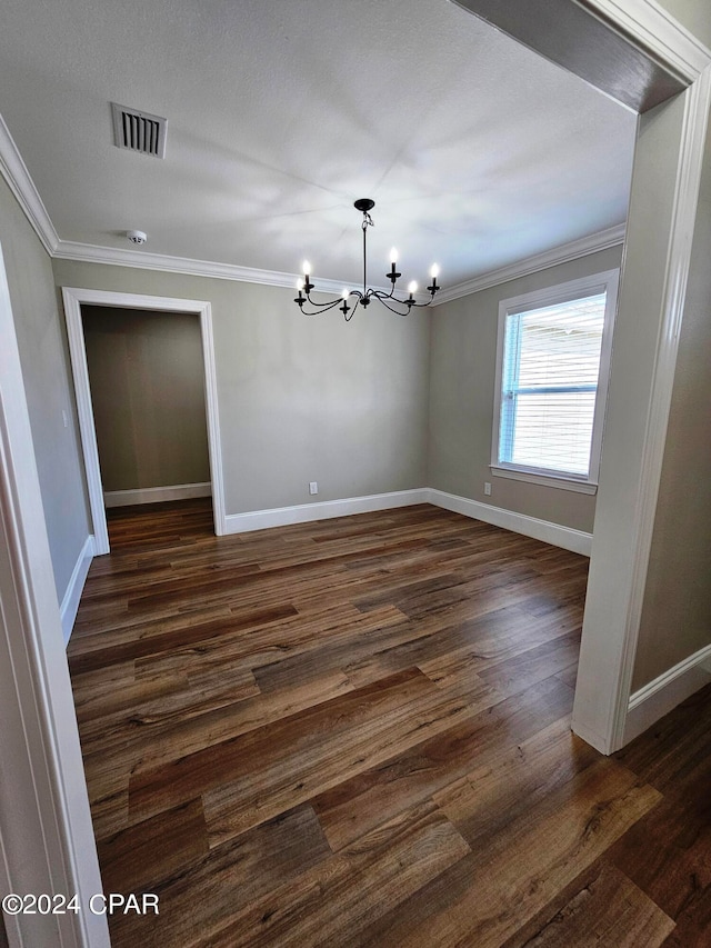 spare room featuring dark hardwood / wood-style flooring, a notable chandelier, and ornamental molding