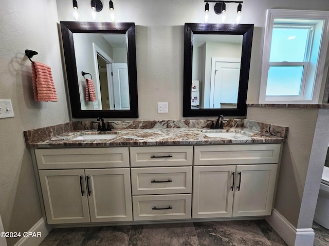 bathroom featuring toilet, tile floors, and dual vanity