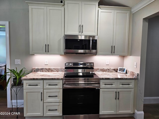 kitchen with white cabinets, appliances with stainless steel finishes, and light stone countertops