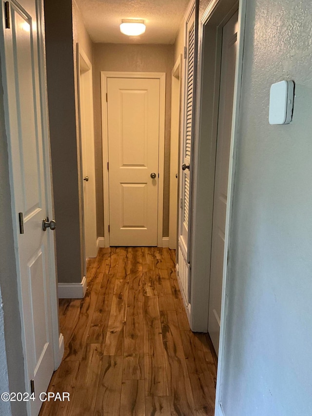 hallway with a textured ceiling and hardwood / wood-style flooring