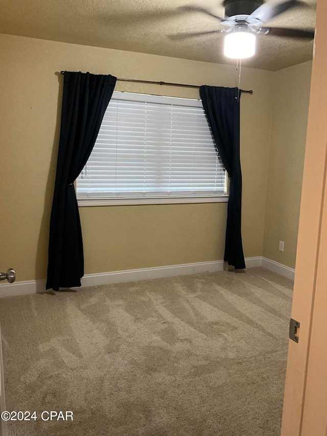 carpeted empty room with ceiling fan and a textured ceiling