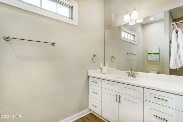 bathroom featuring hardwood / wood-style flooring, plenty of natural light, vanity, and toilet