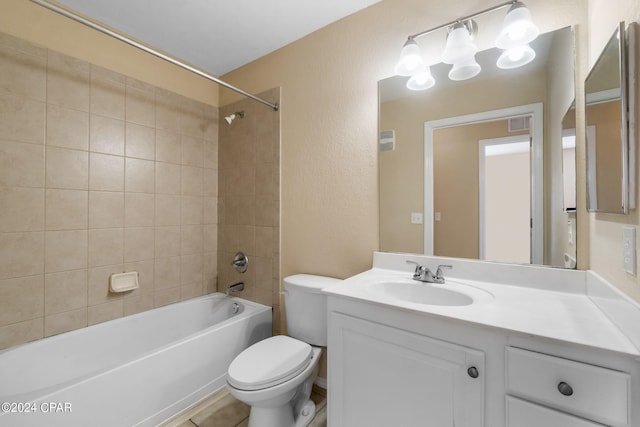 full bathroom featuring vanity, tiled shower / bath combo, and toilet