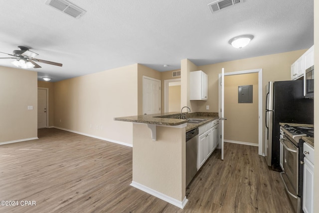 kitchen featuring white cabinetry, a kitchen breakfast bar, kitchen peninsula, appliances with stainless steel finishes, and hardwood / wood-style flooring