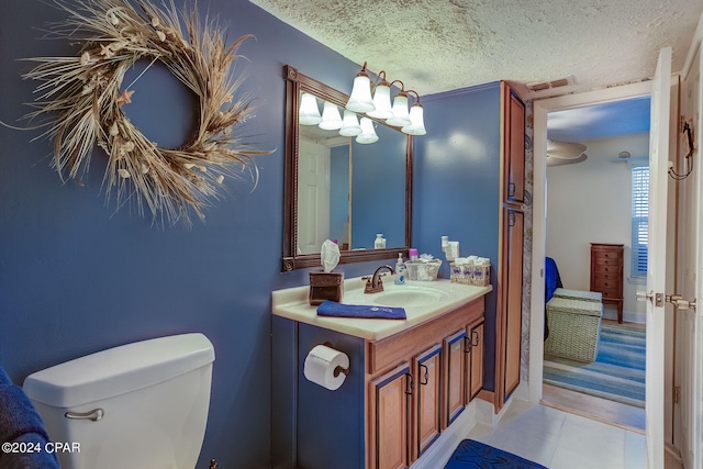 bathroom featuring tile floors, toilet, oversized vanity, and a textured ceiling