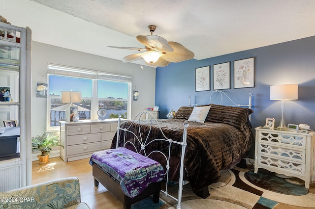 bedroom featuring light hardwood / wood-style flooring, ceiling fan, and a textured ceiling