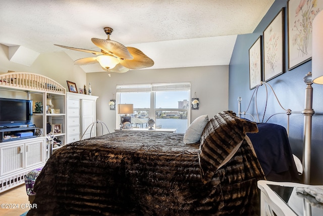 bedroom with ceiling fan, vaulted ceiling, and a textured ceiling