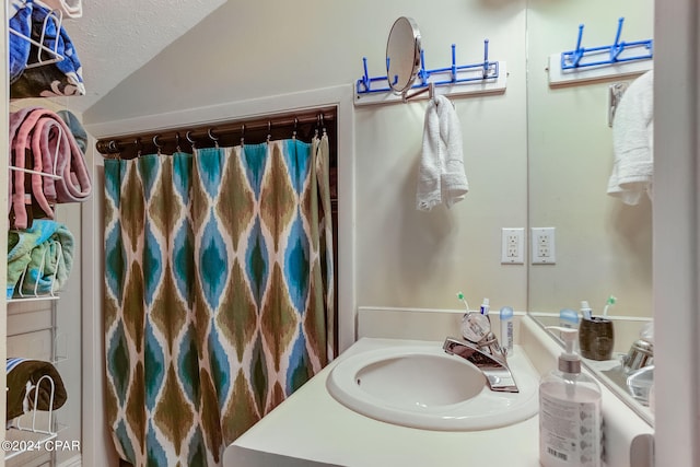 bathroom featuring oversized vanity, vaulted ceiling, and a textured ceiling