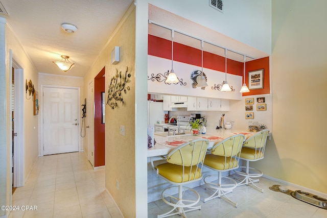 kitchen featuring white cabinets, decorative light fixtures, white appliances, and light tile flooring