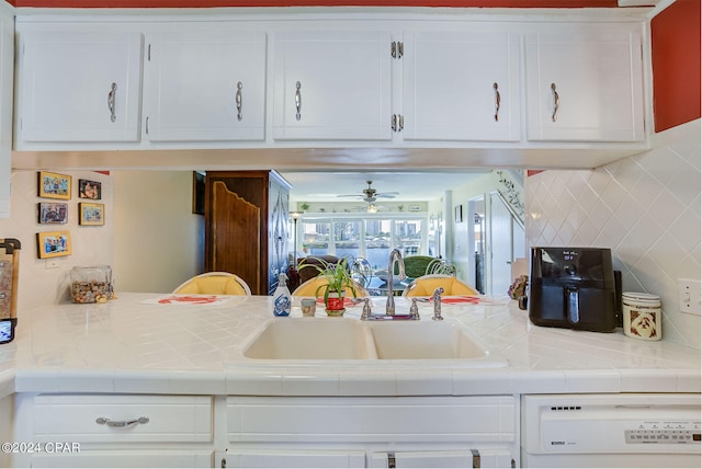 kitchen with dishwashing machine, tile counters, tasteful backsplash, white cabinetry, and sink