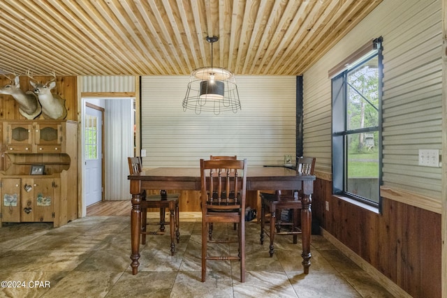 tiled dining room featuring wood walls and wood ceiling