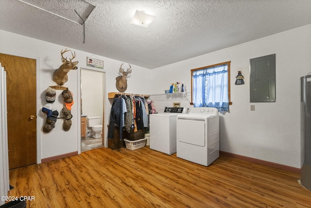 clothes washing area with light hardwood / wood-style flooring, a textured ceiling, and washer and dryer