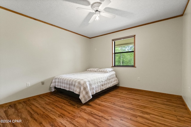 bedroom featuring a textured ceiling, ceiling fan, hardwood / wood-style flooring, and ornamental molding