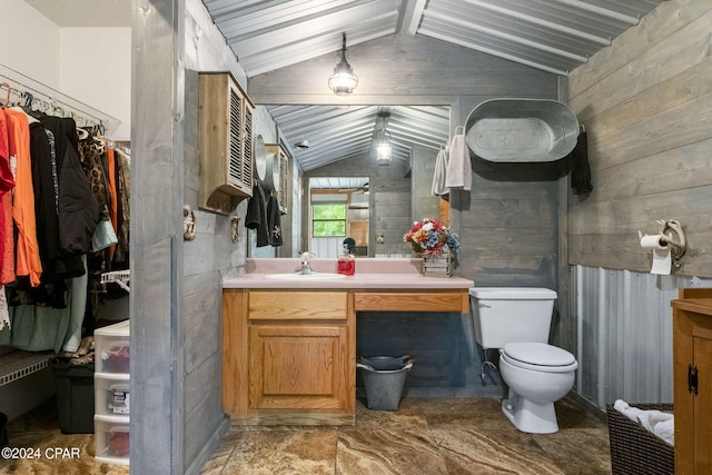 bathroom featuring lofted ceiling with beams, vanity with extensive cabinet space, toilet, and wooden walls