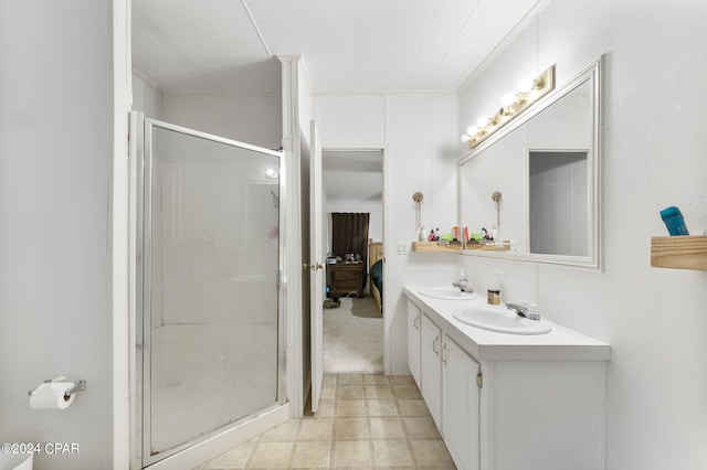 bathroom with double sink vanity, an enclosed shower, tile floors, and a textured ceiling