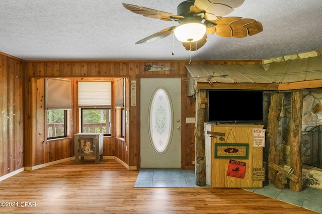 foyer with wood-type flooring, a textured ceiling, ceiling fan, and wooden walls