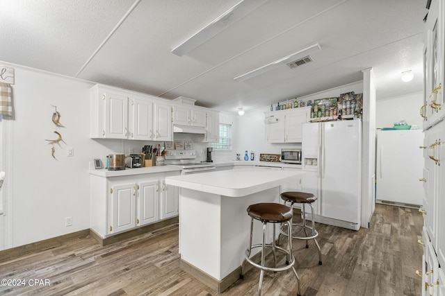 kitchen featuring white appliances, a center island, hardwood / wood-style flooring, and white cabinetry