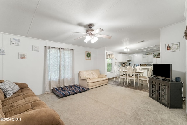 carpeted living room featuring ornamental molding and ceiling fan