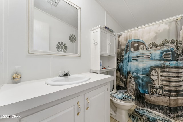 bathroom with tile floors, vaulted ceiling, toilet, and vanity