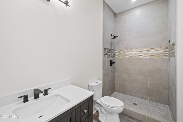 bathroom with vanity, tiled shower, and toilet