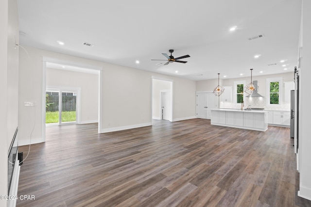 unfurnished living room featuring ceiling fan, wood-type flooring, and plenty of natural light