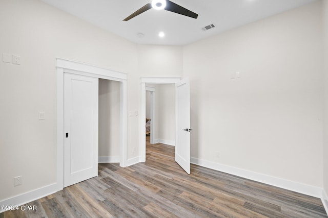 unfurnished bedroom featuring a closet, wood-type flooring, and ceiling fan