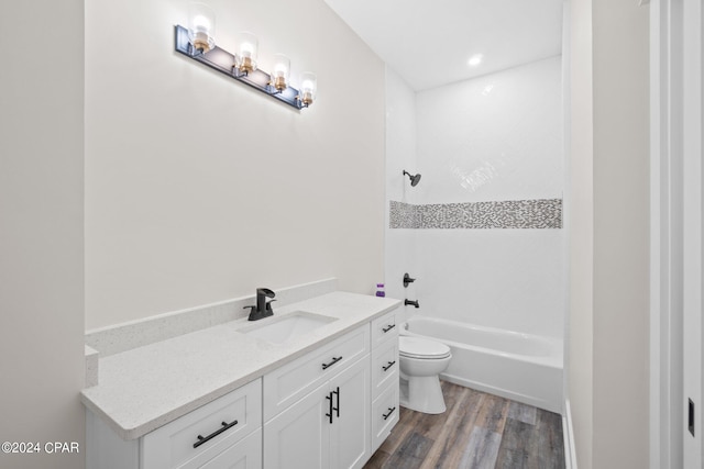 full bathroom featuring vanity, hardwood / wood-style flooring, tiled shower / bath, and toilet