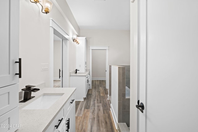 bathroom with hardwood / wood-style flooring, vanity, and a tile shower