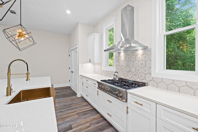 kitchen featuring wall chimney range hood, dark hardwood / wood-style flooring, pendant lighting, stainless steel gas stovetop, and decorative backsplash