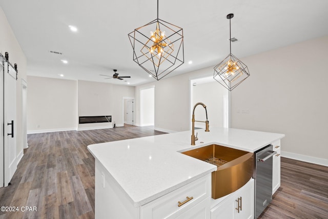 kitchen featuring hardwood / wood-style flooring, a barn door, stainless steel dishwasher, a kitchen island with sink, and ceiling fan